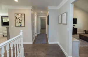 Corridor with dark wood-type flooring, an upstairs landing, recessed lighting, and crown molding