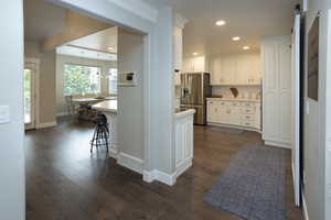Kitchen with white cabinetry, stainless steel fridge with ice dispenser, dark wood-style floors, light countertops, and recessed lighting