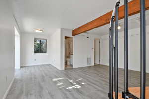 Empty room featuring beamed ceiling and light wood finished floors