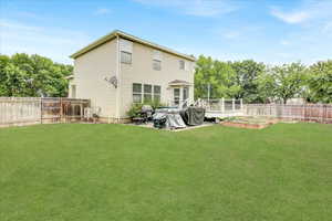 Rear view of property with a fenced backyard, a deck, a vegetable garden, and view of scattered trees