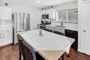 Kitchen with stainless steel appliances, white cabinets, decorative backsplash, dark wood-style floors, and recessed lighting