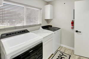 Washroom featuring light wood-style floors, washer and dryer, and cabinet space