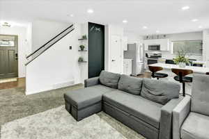 Living area with light carpet and recessed lighting