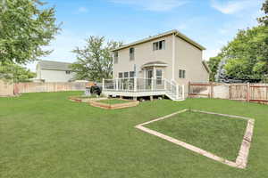 Rear view of house with a vegetable garden, a wooden deck, and a fenced backyard