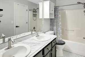Bathroom featuring double vanity, shower / bathtub combination with curtain, and light tile patterned floors