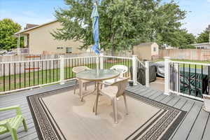Deck featuring outdoor dining space, a fenced backyard, and a shed