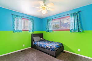Carpeted bedroom with multiple windows and a ceiling fan