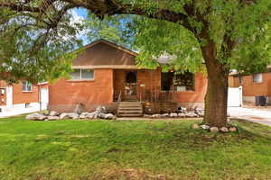 View of front facade featuring brick siding, a front yard, and a garage