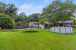 View of yard with a trampoline, a playground, and view of wooded area