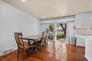 Dining space with dark wood finished floors, recessed lighting, and a textured ceiling
