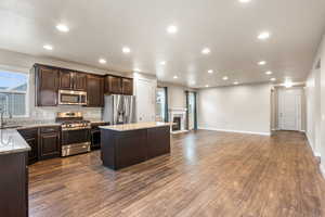 Kitchen featuring dark brown cabinetry, stainless steel appliances, a center island, open floor plan, and recessed lighting