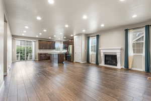 Unfurnished living room featuring a glass covered fireplace, dark wood-style flooring, and recessed lighting