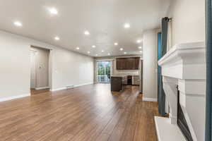 Unfurnished living room featuring a fireplace with raised hearth, recessed lighting, and dark wood-style floors