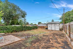 Fenced backyard with a storage unit and a patio