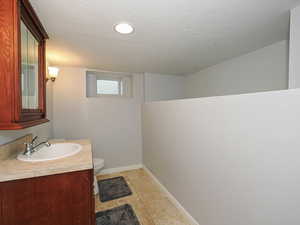 Half bathroom featuring vanity, a textured ceiling, and light tile patterned floors