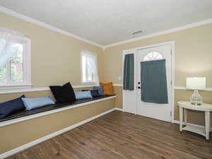 Entryway featuring dark wood-type flooring, crown molding, and a textured ceiling