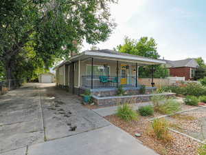 View of front of property with an outdoor structure, covered porch, a garage, and driveway
