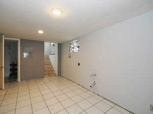 Unfurnished room with a textured ceiling, electric panel, light tile patterned floors, recessed lighting, and stairs