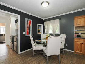 Dining area featuring dark wood-style floors, ornamental molding, a textured ceiling, and washer and clothes dryer