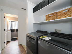 Washroom with crown molding, light wood-style floors, and washer and dryer