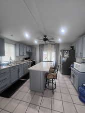 Kitchen with gray cabinetry, a breakfast bar area, light countertops, a ceiling fan, and recessed lighting