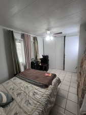 Tiled bedroom featuring a textured ceiling, a ceiling fan, and a closet