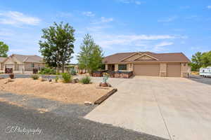 View of front facade with concrete driveway, an attached garage, stone siding, and stucco siding
