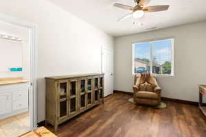Sitting room with a textured ceiling, dark wood-type flooring, and a ceiling fan