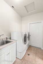 Laundry room with a textured ceiling, light tile patterned flooring, independent washer and dryer, and attic access