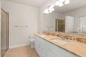 Bathroom with a shower stall, light tile patterned flooring, double vanity, and tasteful backsplash