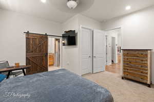 Bedroom featuring light colored carpet, recessed lighting, a ceiling fan, and a barn door