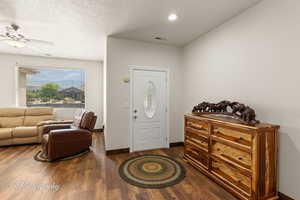 Entryway featuring a textured ceiling, dark wood-type flooring, and ceiling fan