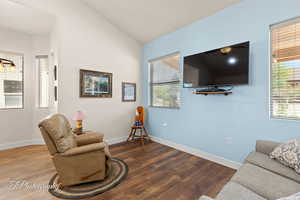 Living area with lofted ceiling, plenty of natural light, and wood finished floors