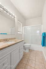 Bathroom featuring enclosed tub / shower combo, light tile patterned floors, and vanity