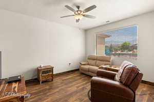 Living room featuring dark wood-style floors, a textured ceiling, and ceiling fan