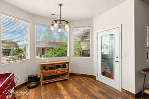 Dining area featuring dark wood-style floors, a chandelier, and a textured ceiling