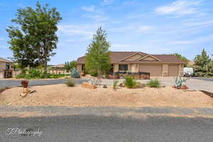 View of front of home with driveway, an attached garage, stone siding, and stucco siding