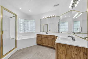 Bathroom featuring a garden tub, a stall shower, double vanity, light tile patterned floors, and recessed lighting