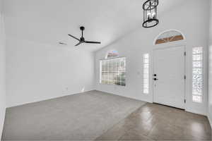Entryway with light colored carpet, a ceiling fan, and high vaulted ceiling