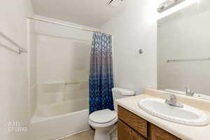 Bathroom featuring shower / tub combo, a textured ceiling, light tile patterned floors, and vanity