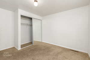 Unfurnished bedroom with a textured ceiling, carpet floors, and a closet
