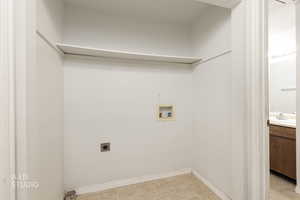 Laundry room featuring electric dryer hookup, hookup for a washing machine, and light tile patterned floors