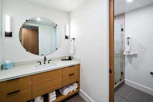 Full bathroom with vanity, dark tile patterned flooring, and a shower stall