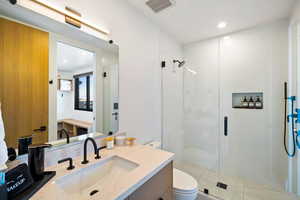 Bathroom with a stall shower, vanity, and recessed lighting