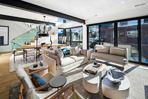 Living room featuring wood finished floors, a chandelier, stairs, and recessed lighting