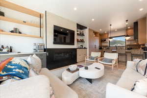 Living room with built in features, a glass covered fireplace, and recessed lighting