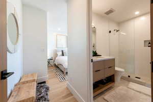 Bathroom featuring vanity, walk in shower, light wood finished floors, and recessed lighting