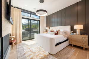 Bedroom featuring a decorative wall, a fireplace, access to outside, and light wood-type flooring