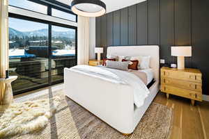 Bedroom featuring a mountain view, wood finished floors, access to exterior, and a decorative wall