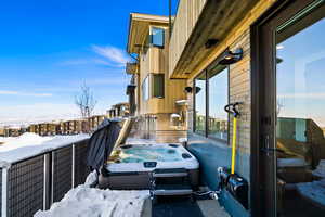 Snow covered back of property with a hot tub